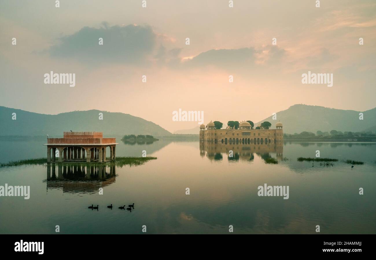View across peaceful lake with deserted Royal palace surrounded by lake and Aravalli hills as dawn breaks in Jaipur, Rajasthan, India. Stock Photo