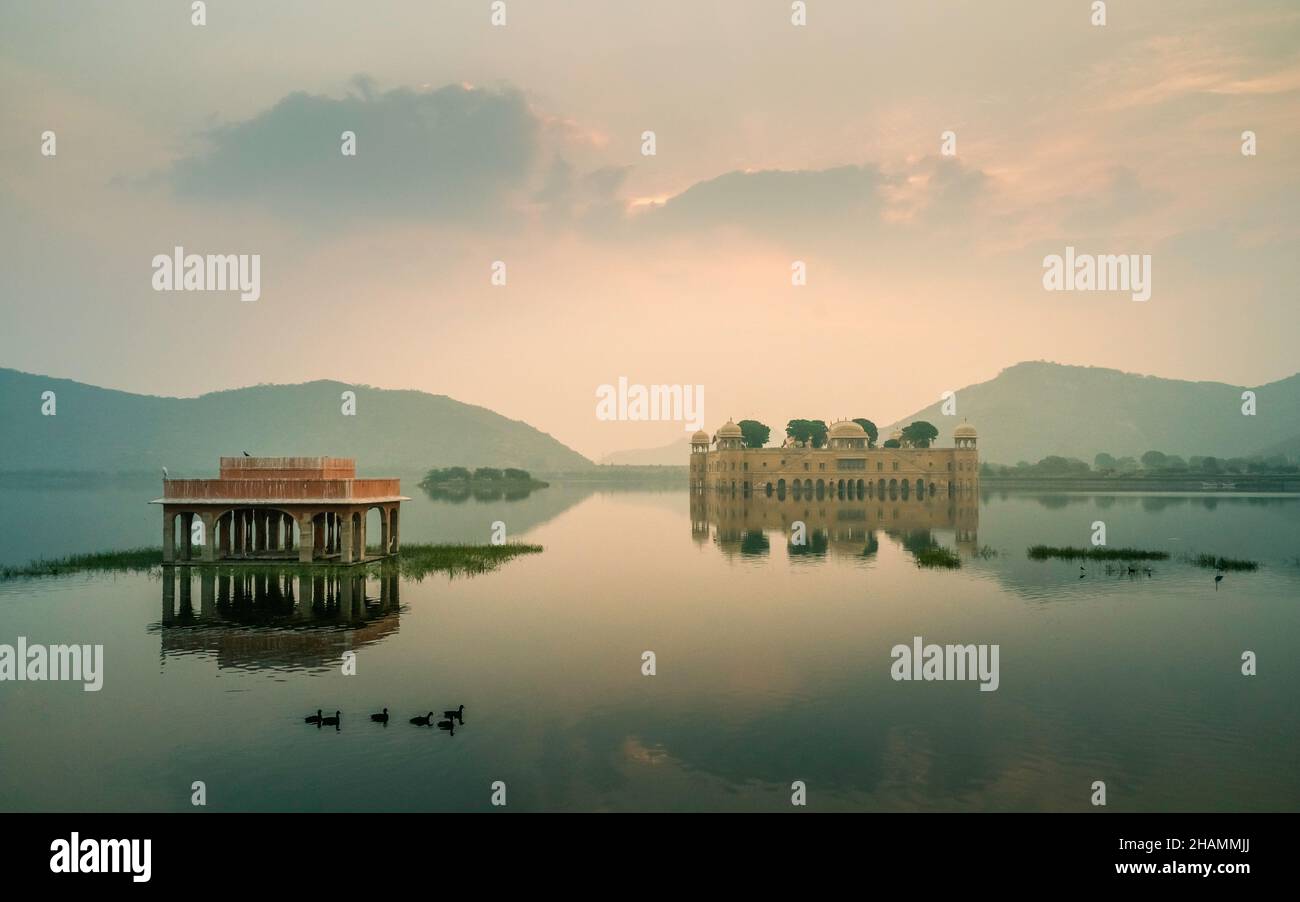 View across peaceful lake with deserted Royal palace surrounded by lake and Aravalli hills as dawn breaks in Jaipur, Rajasthan, India. Stock Photo