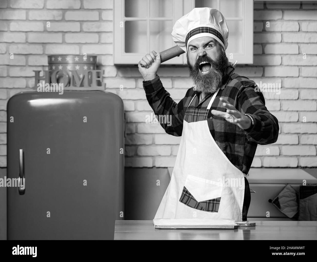 Cooking food concept. Holding rolling pin, clenching fist, screaming. Stock Photo