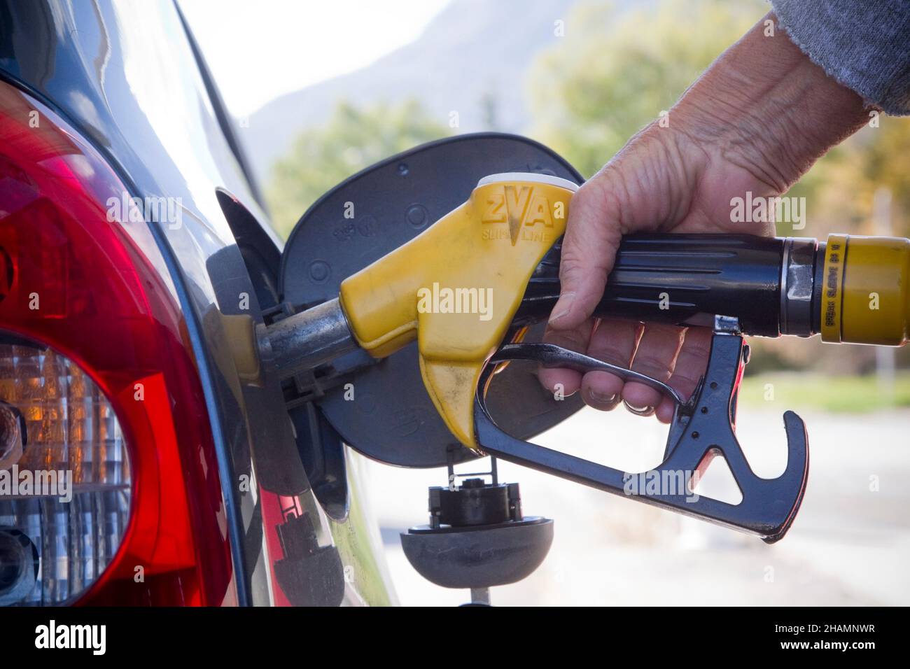 Someone filling a tank with petrol at a gas station Stock Photo