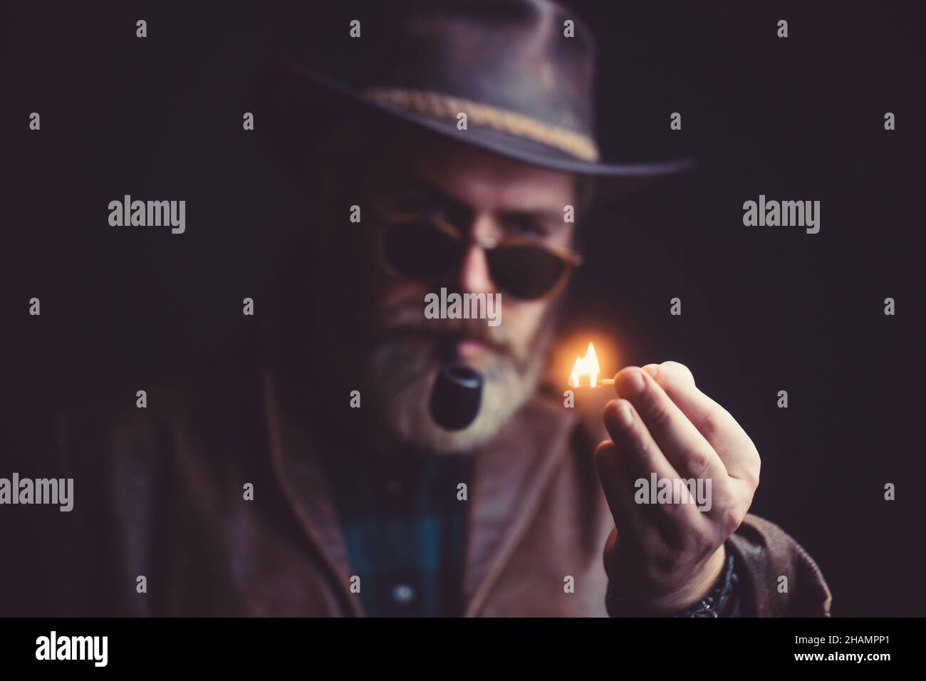 Guy smokes tobacco pipe. Hipster with beard and mustache on serious face. Stock Photo