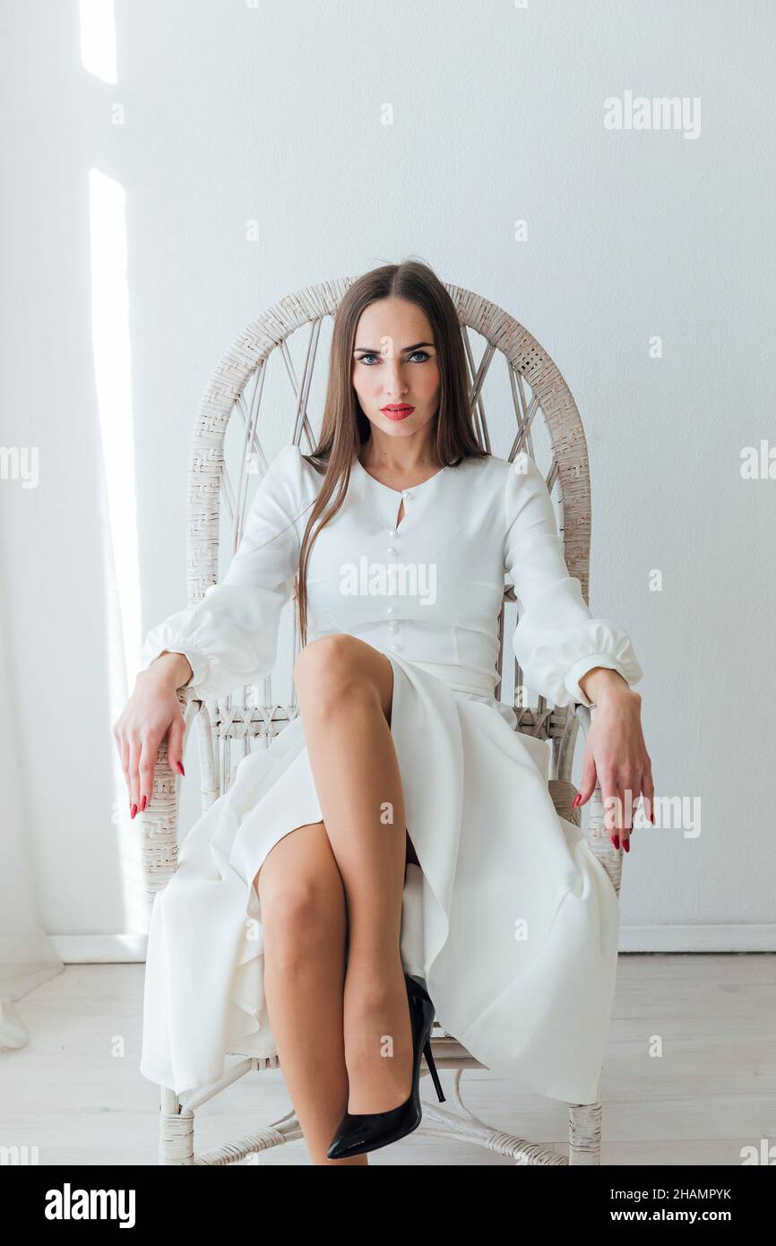 a beautiful woman in a white dress sits in a braided chair Stock Photo ...