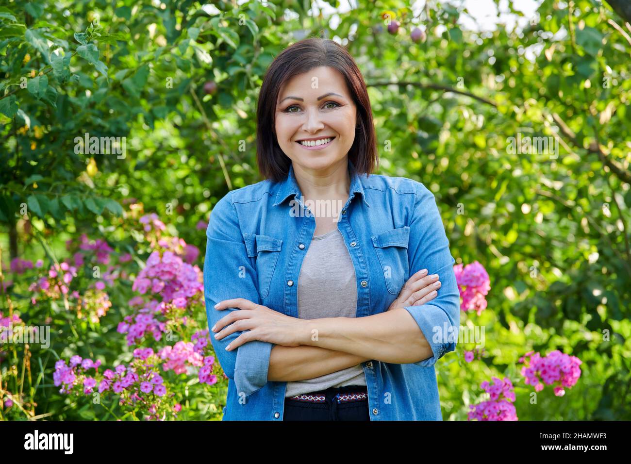 Portrait of smiling confident middle aged woman with crossed arms in ...