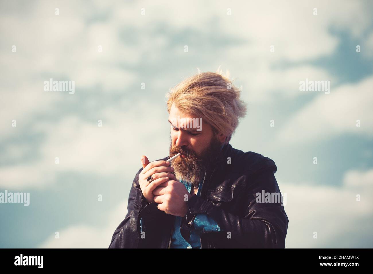 Brutal man with beard on the top of the high building with cityscape on background. Stock Photo