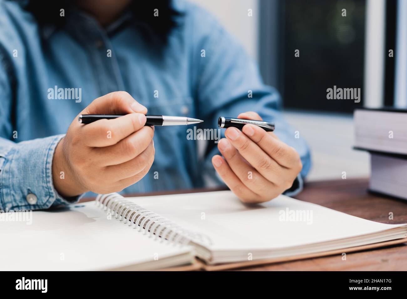 woman holding a pen sitting on a desk writing Stock Photo - Alamy