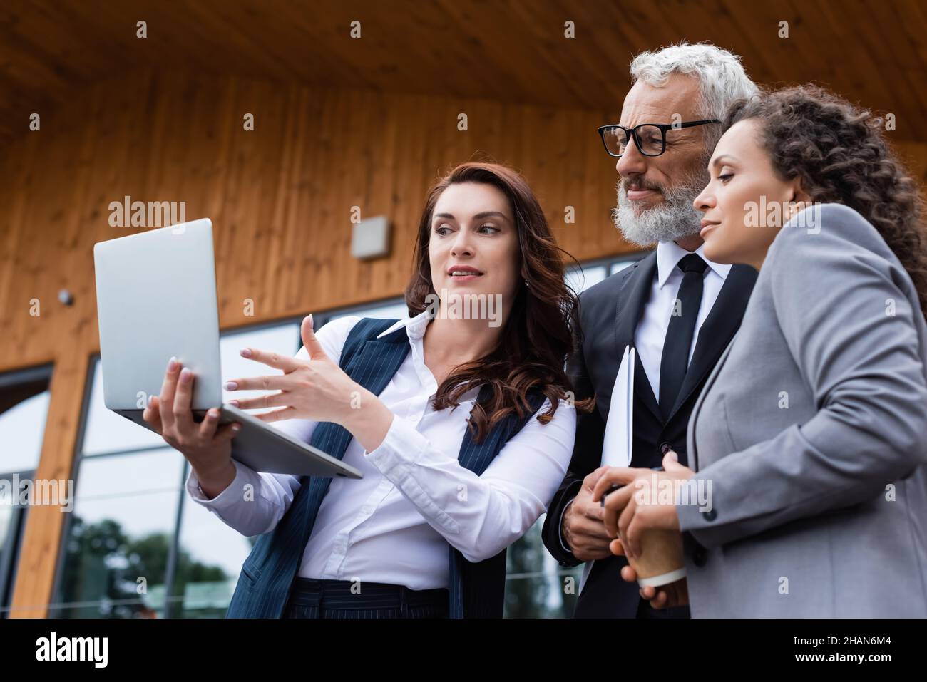 real estate agent pointing at laptop near interracial business partners ...