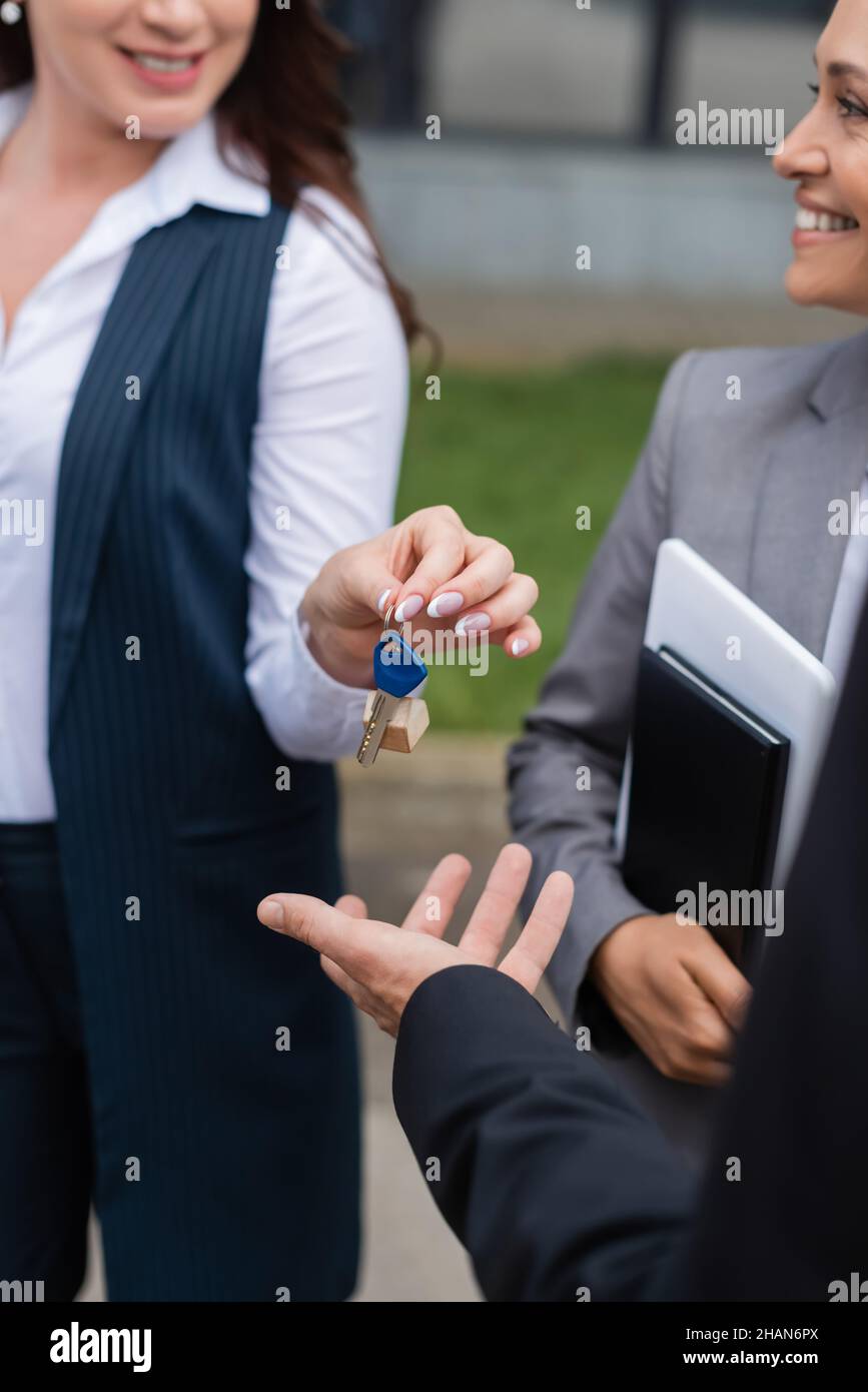 blurred real estate agent giving key to businessman near his smiling ...