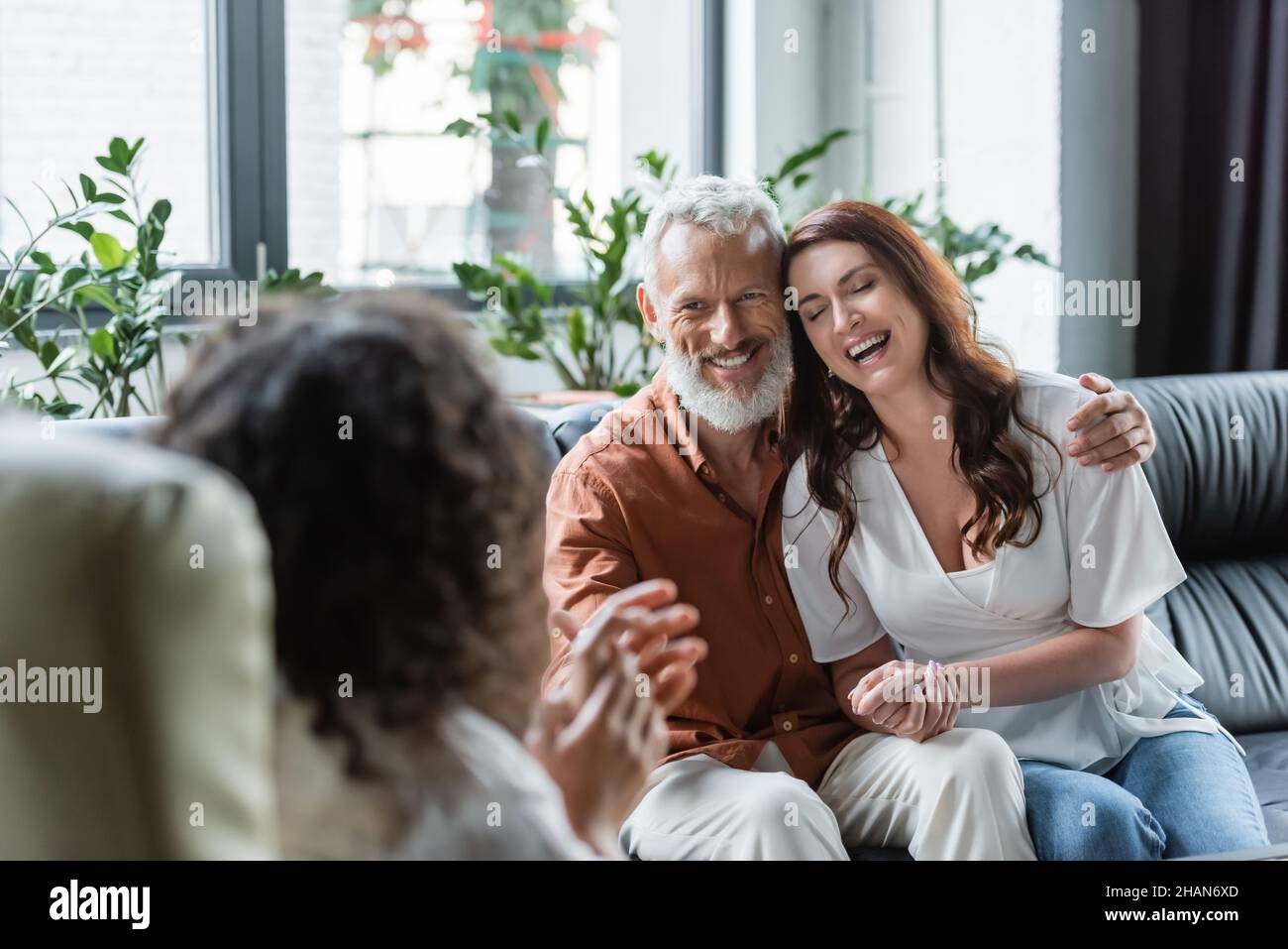 cheerful man hugging happy wife during consultation with blurred ...