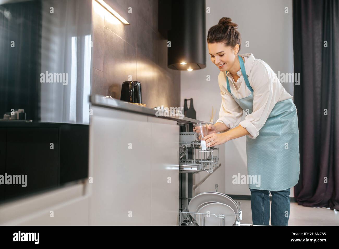 Young woman in the kitchen looking busy while washing the plates Stock Photo