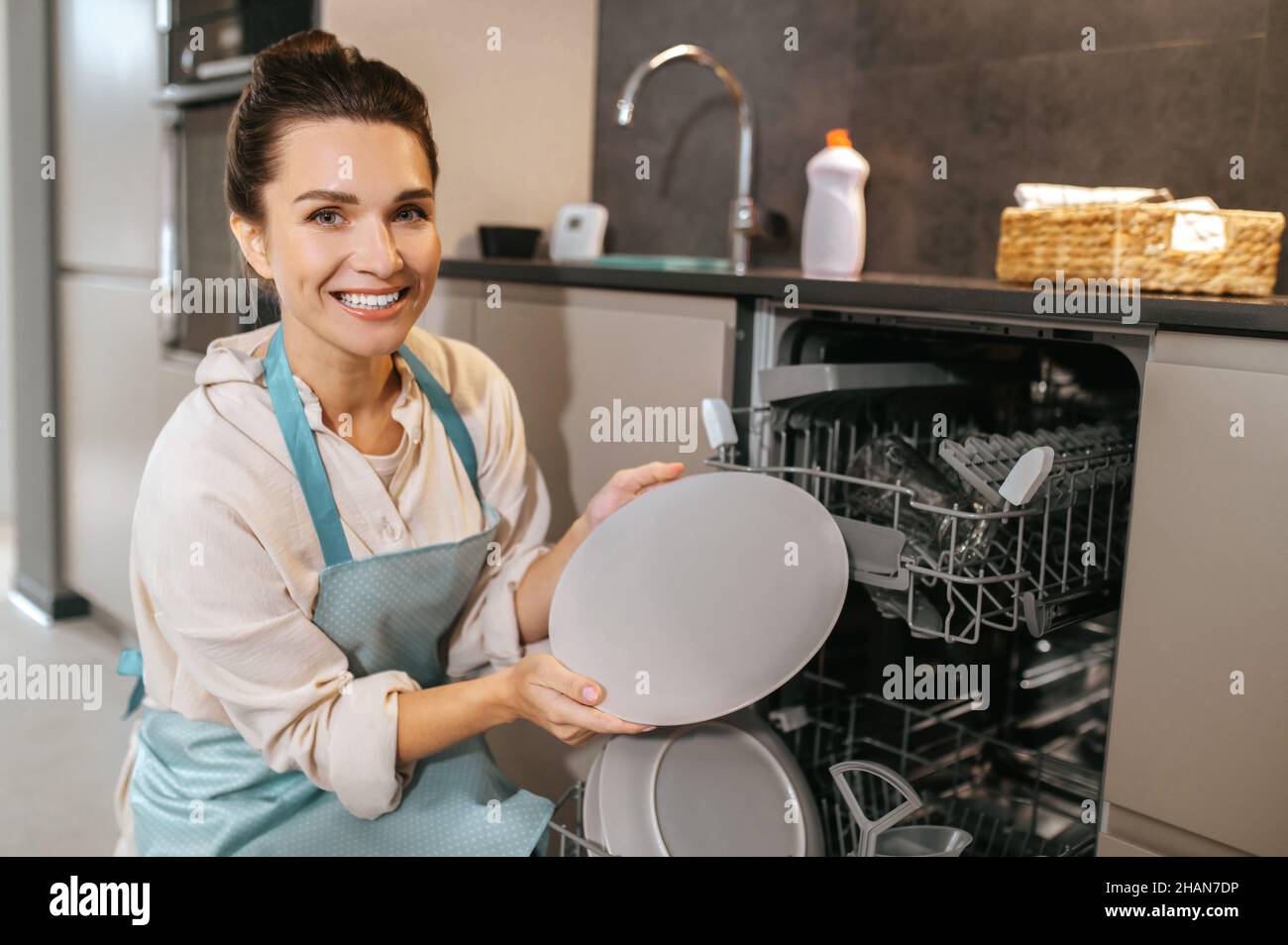 Young woman in apron cleaning the crockery Stock Photo