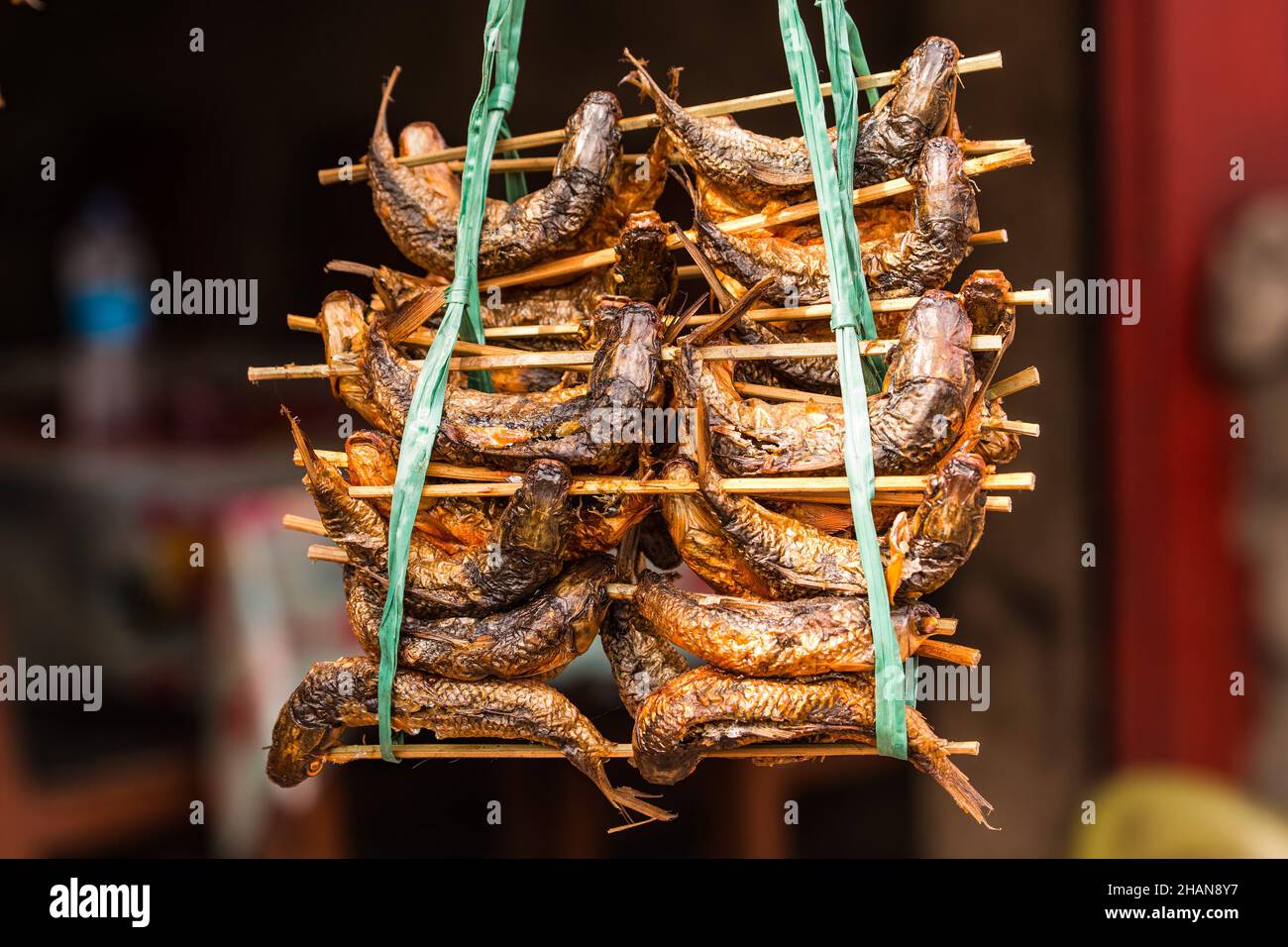 Whole smoked dried fish for sale in a bamboo rack in a roadside