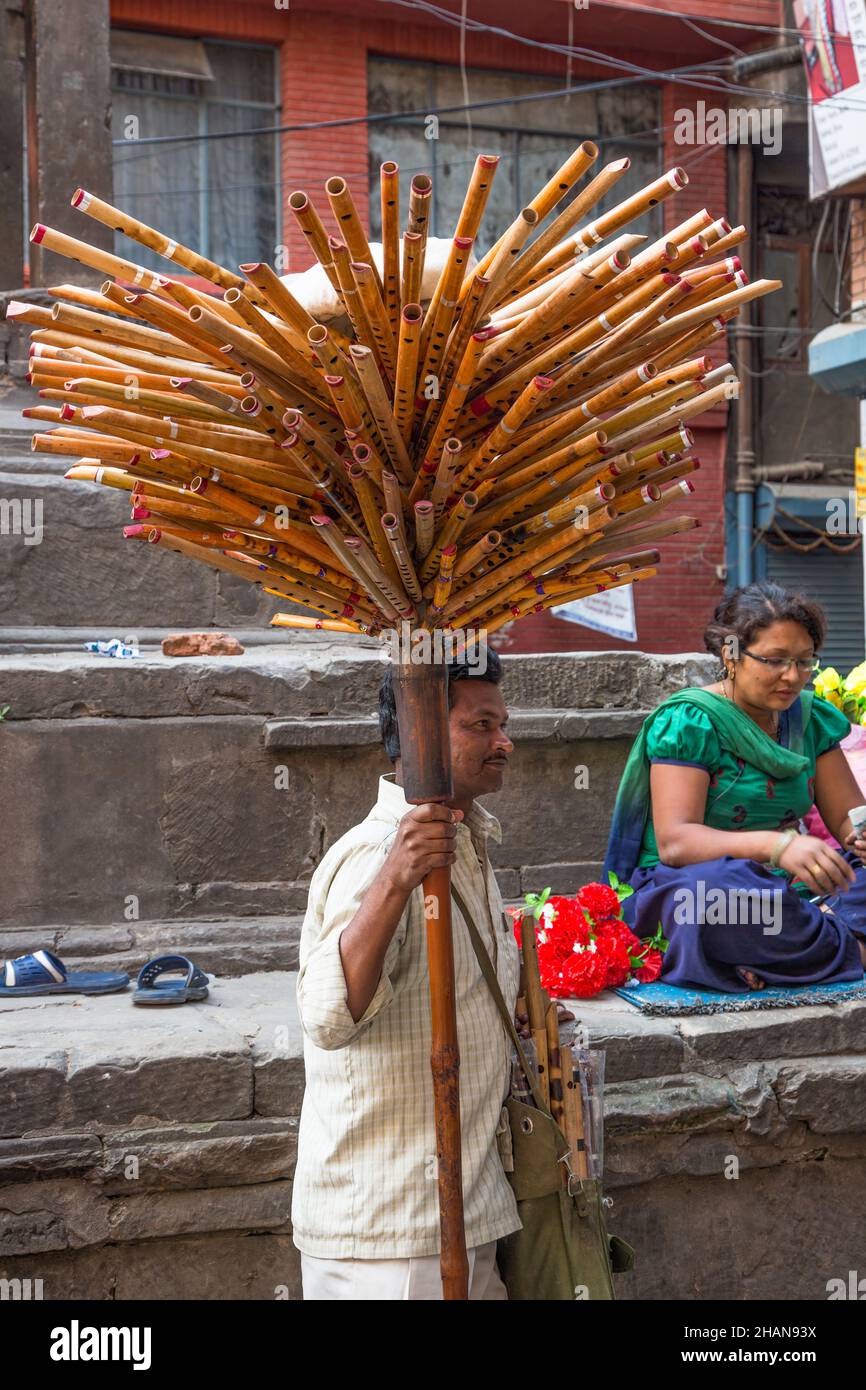 A vendor selling bamboo flutes arranged on a pole like a tree in a