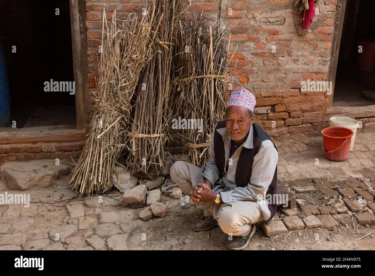 A Nepali man in a dhaka topi hat in front of his house in the medieval Newari village of Khokana in the Kathmandu Valley of Nepal. Stock Photo