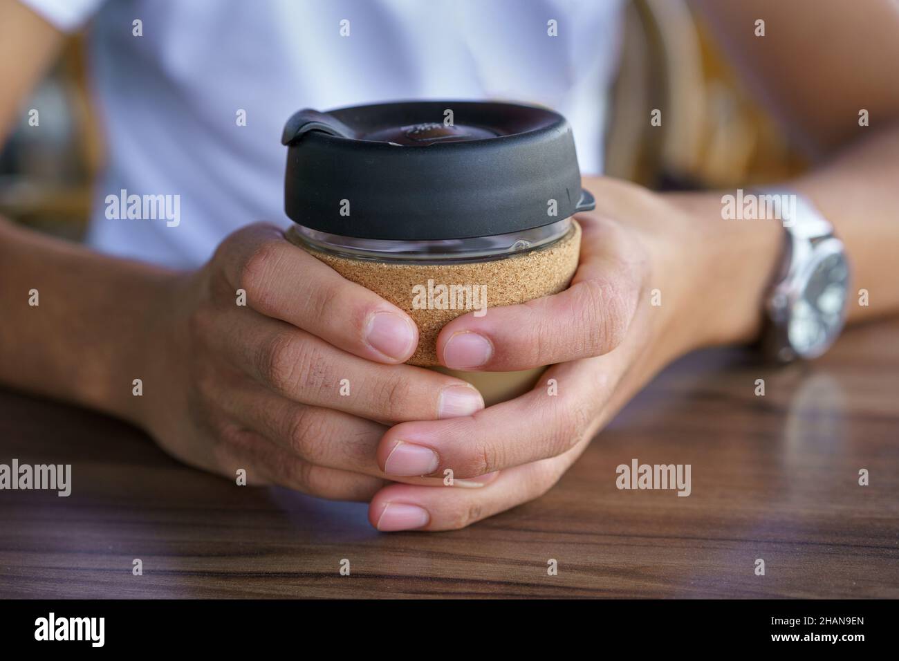 Male hands hold reusable coffee mug. Young man drink coffee from reusable travel coffee cup. Teenager holding reusable coffee mug. Sustainable lifestyle. Eco friendly concept. Stock Photo