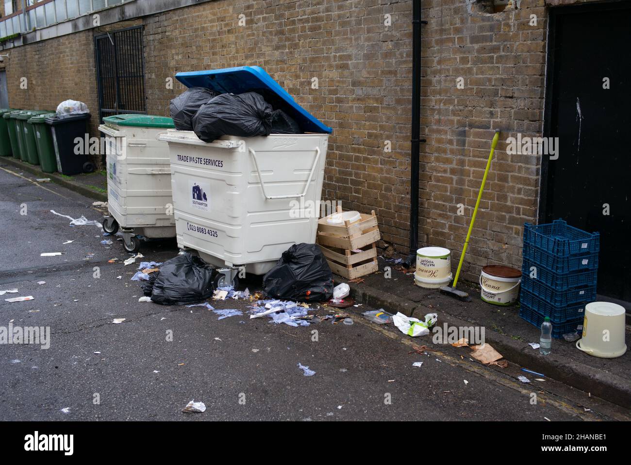 Overfilled and spilling industrial rubbish bin at the back of a business in Southampton City Centre. Stock Photo