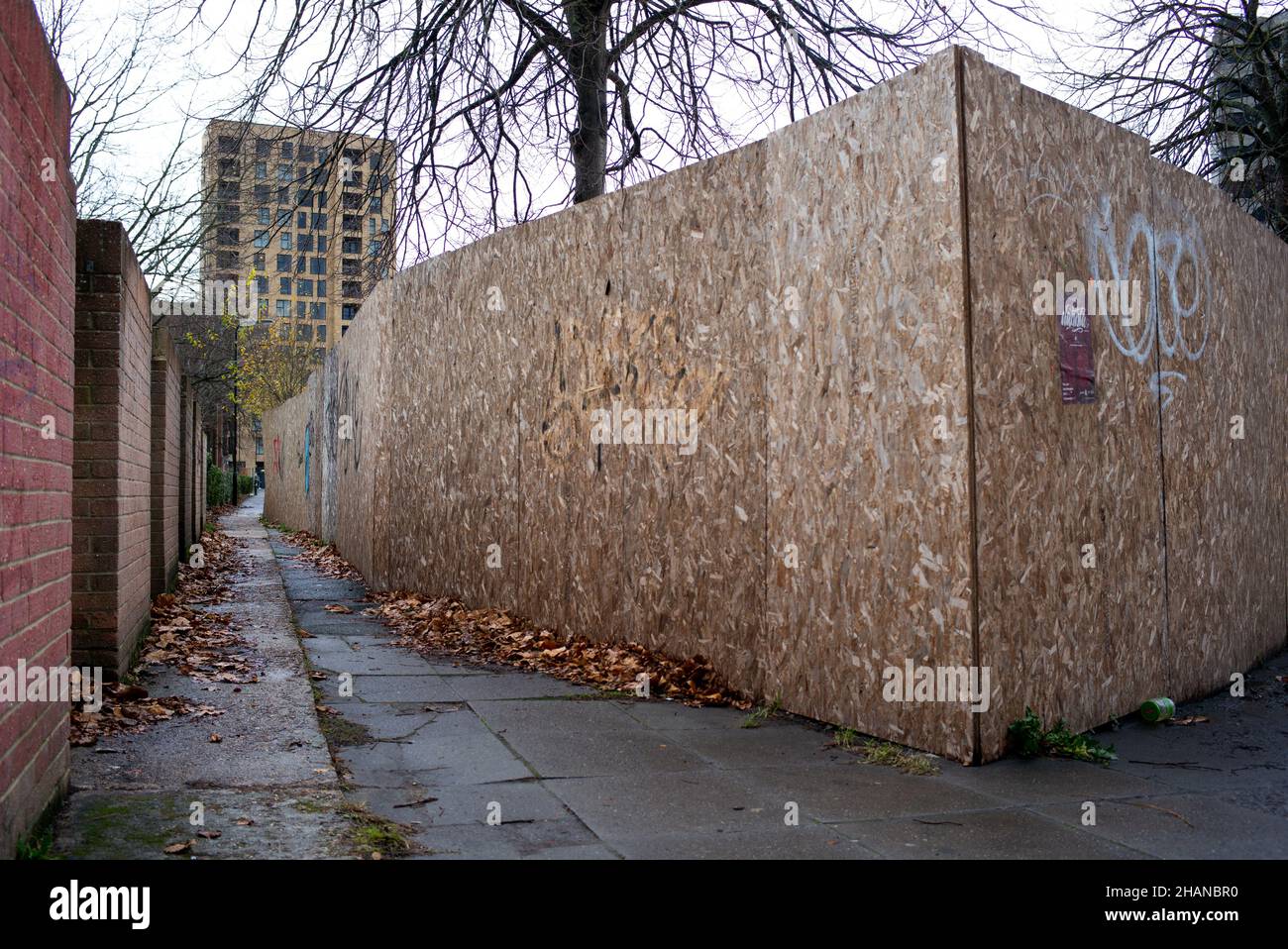 A city alleyway with one side brick wall the other chipboard from a building site creating an eerie scene which could be used in a conceptual way. Stock Photo