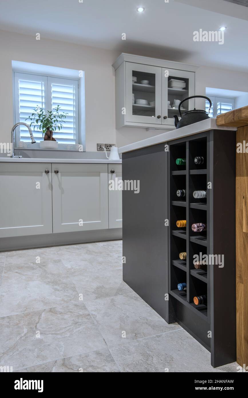 A light,contemporary, fitted kitchen with a wine rack,island,blinds (using mixed materials including blockwood).Has kitchen island with extractor fan. Stock Photo