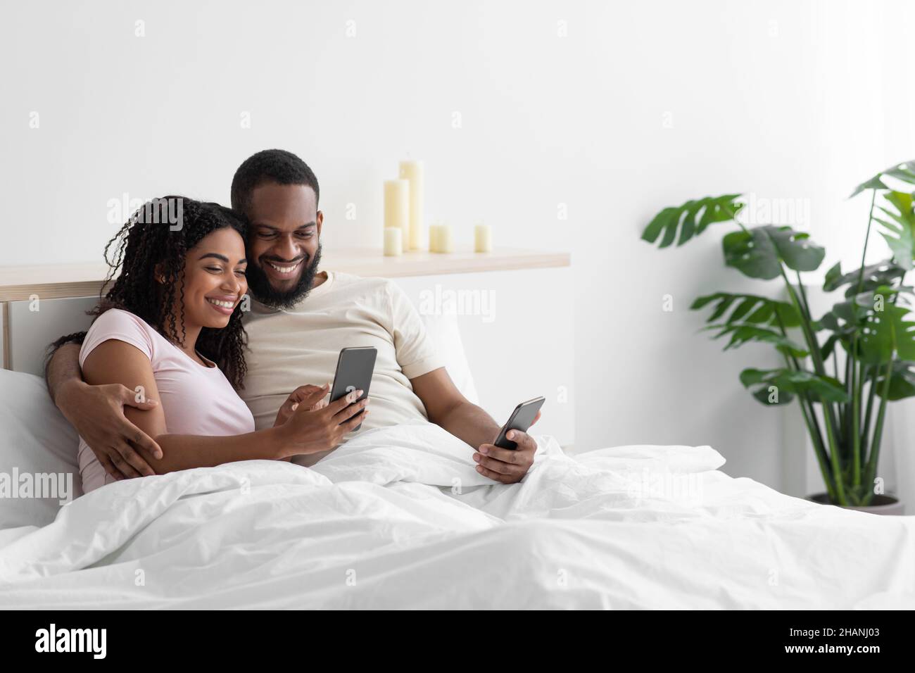 Smiling young african american husband and wife hugging, looking at ...