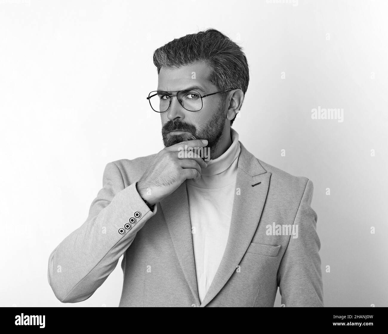 Handsome young businessman thoughtfully scratches his beard . Stock Photo