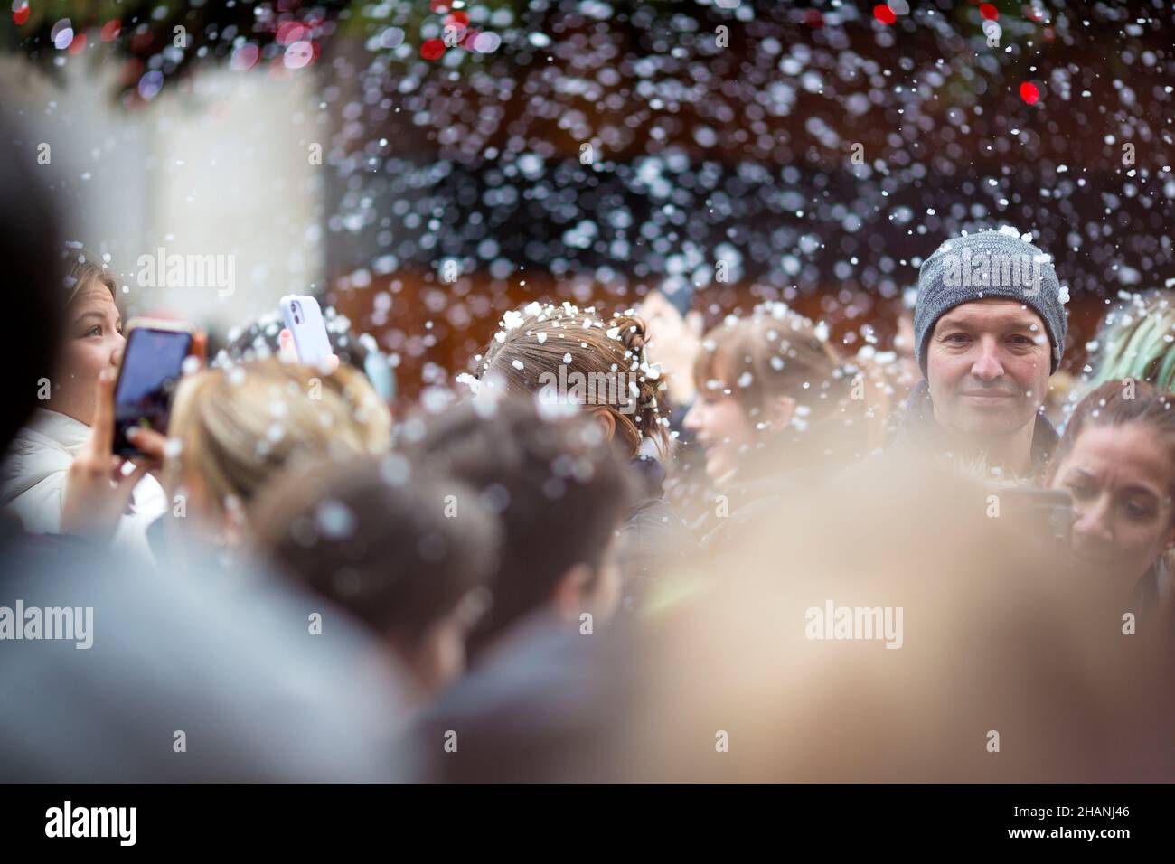 People take photos of flakes of artificial snow in Covent Garden in