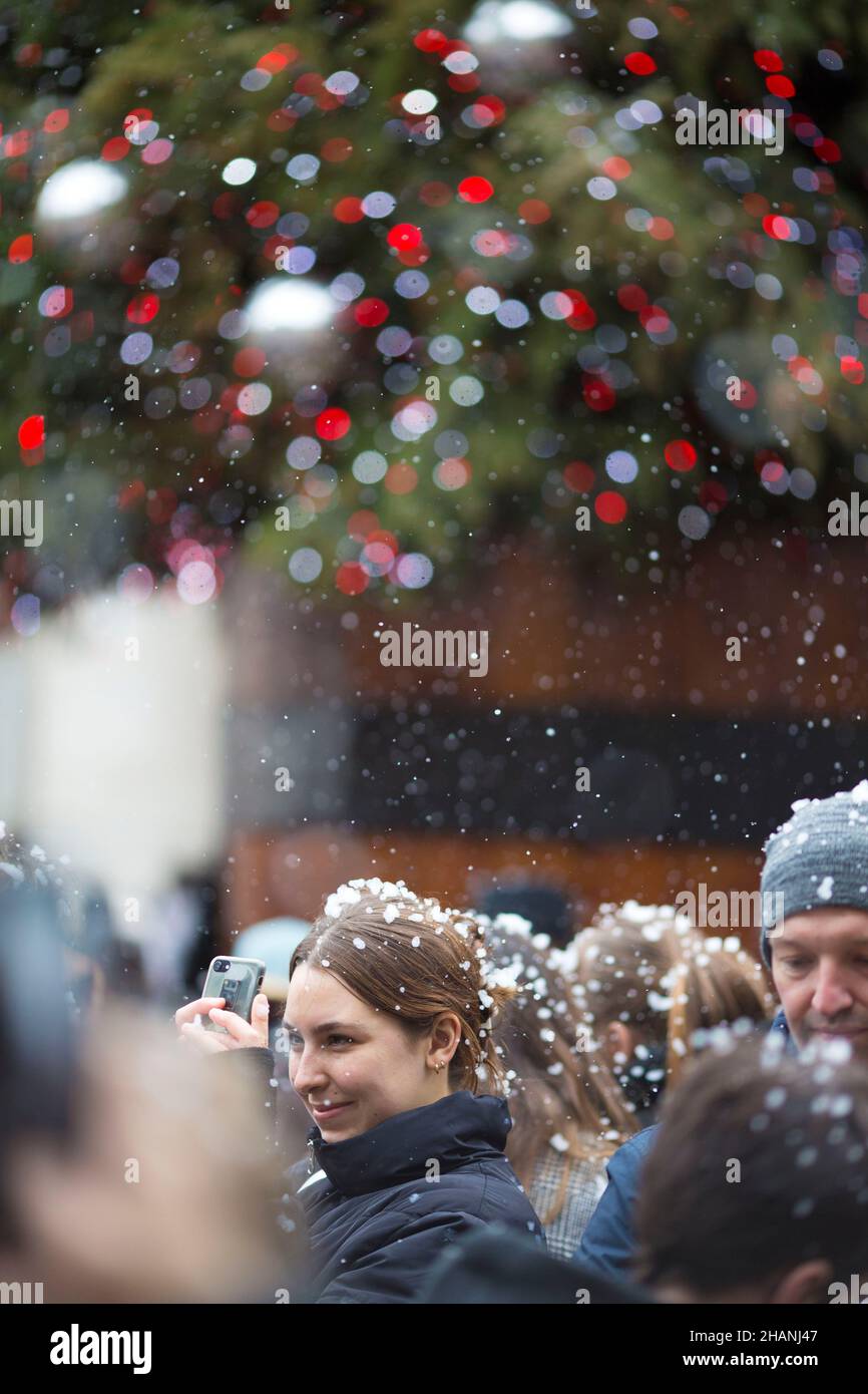 People take photos of flakes of artificial snow in Covent Garden in