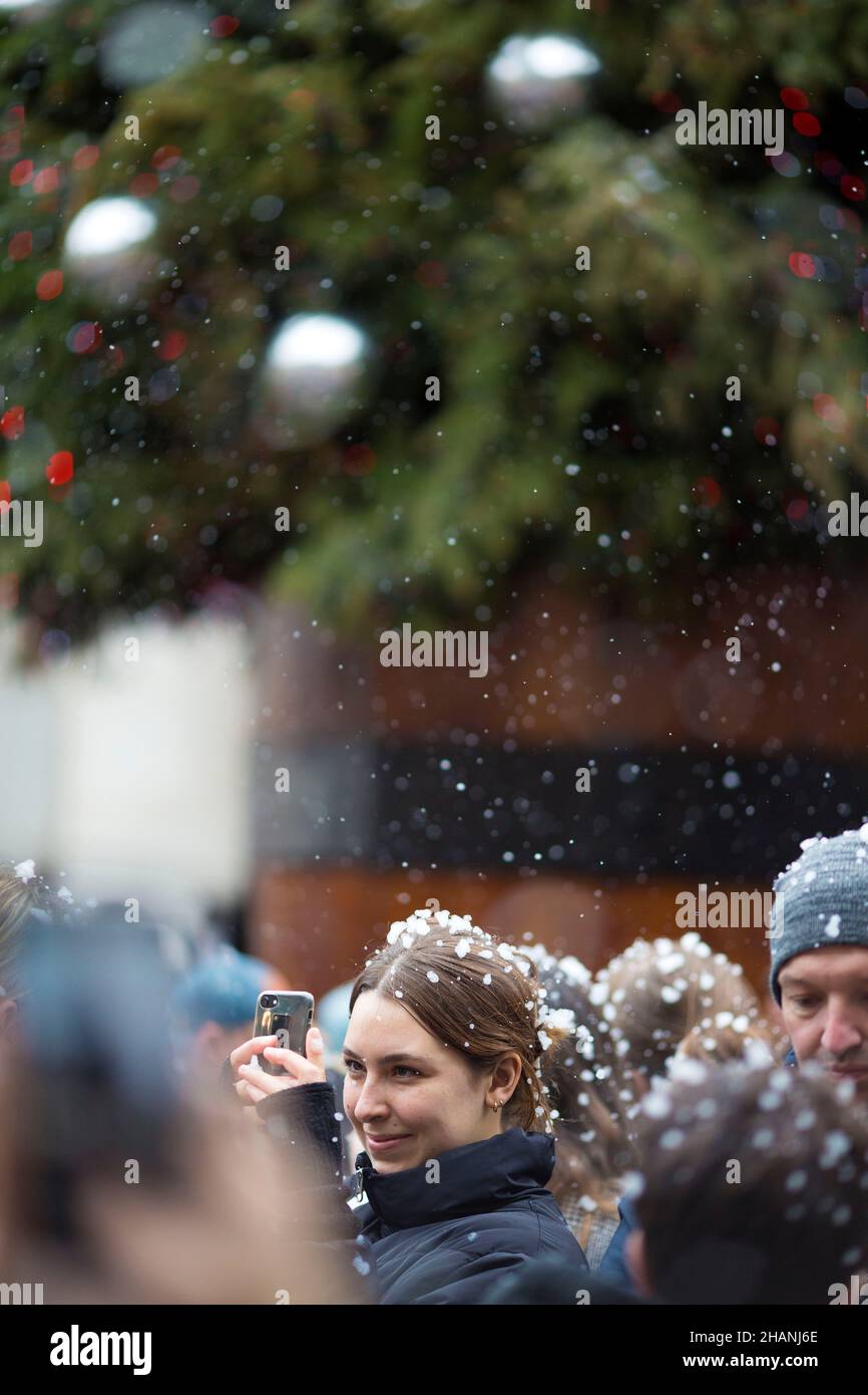 People take photos of flakes of artificial snow in Covent Garden in