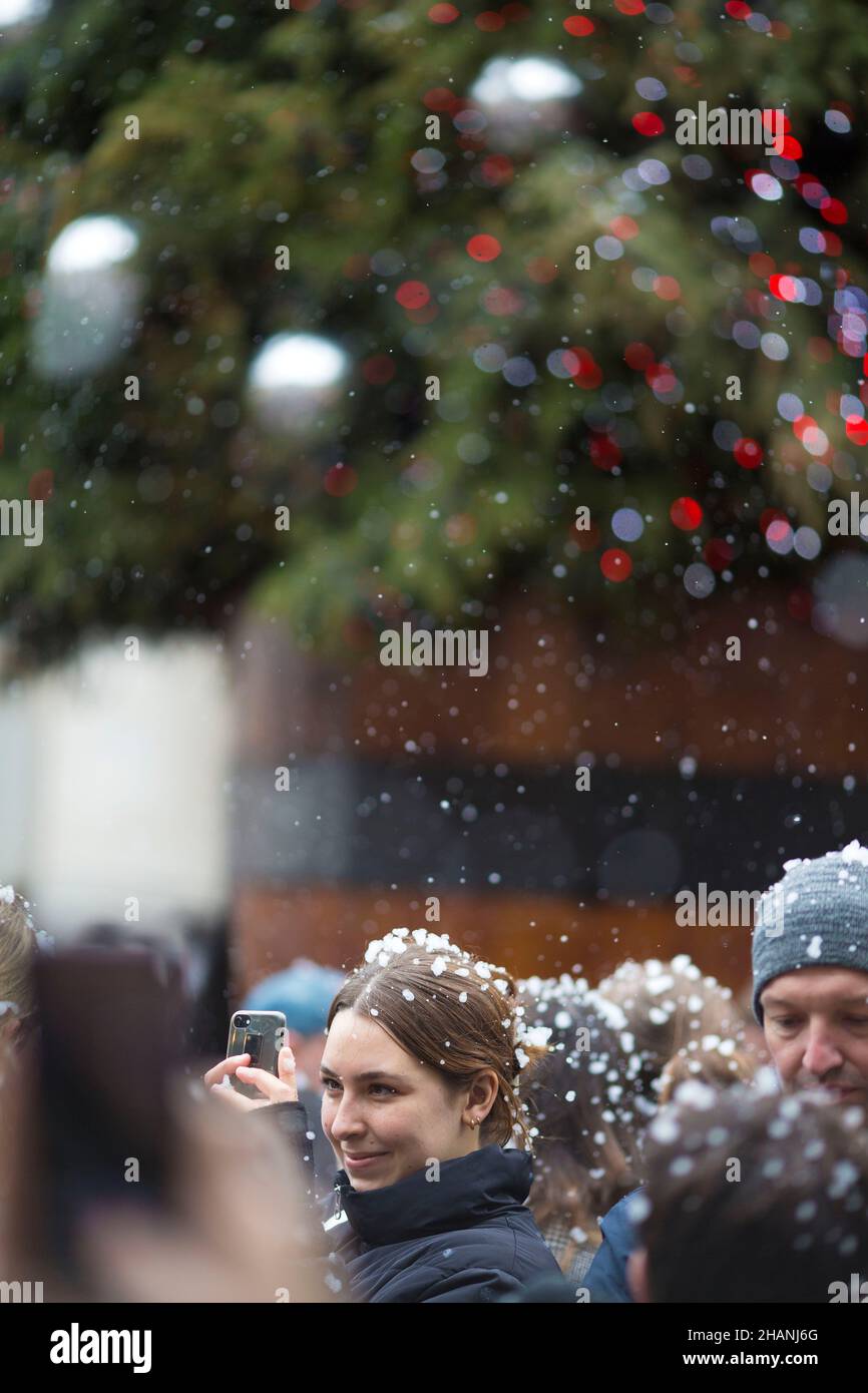 People take photos of flakes of artificial snow in Covent Garden in central London Stock Photo