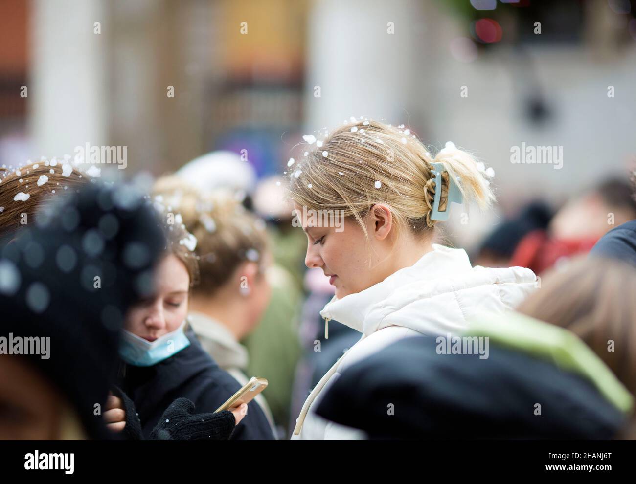 Flakes of artificial snow are seen on the heads of people gathering in