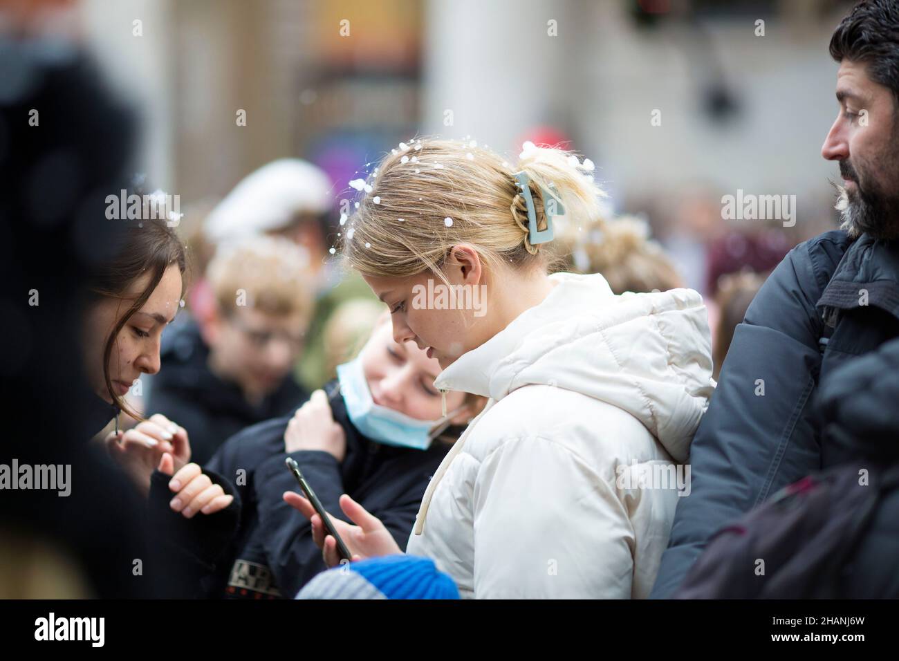 Flakes of artificial snow are seen on the heads of people gathering in