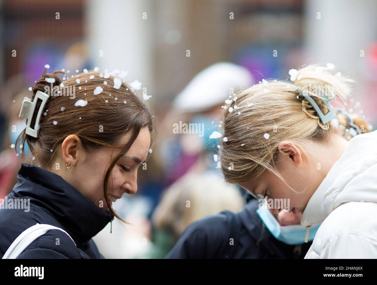 Flakes of artificial snow are seen on the heads of people gathering in