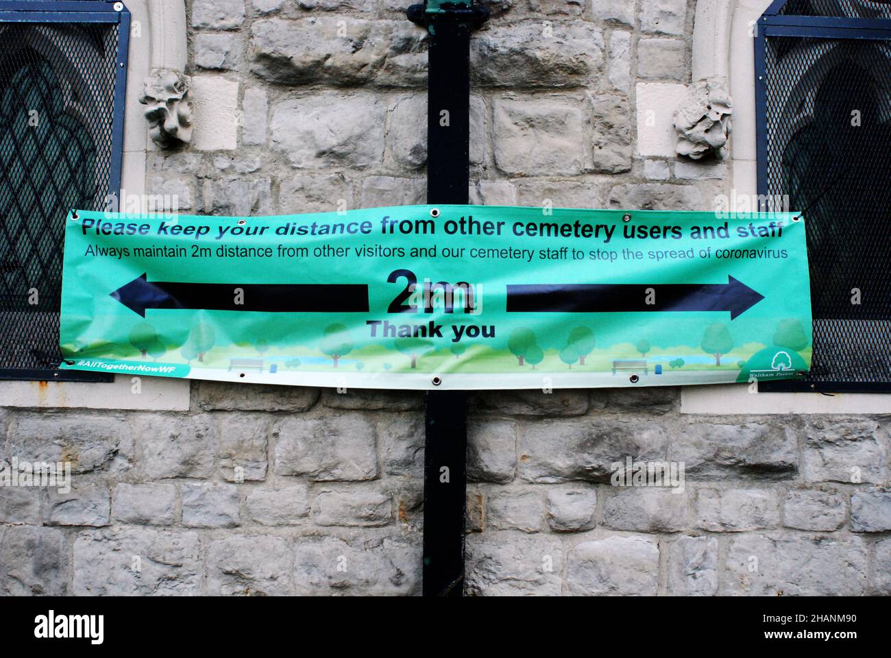 Covid-19 coronavirus sign hanging on a burial chapel /cemetery, reminding people of the two metre apart rule. Social distancing, lockdown, covid rules Stock Photo