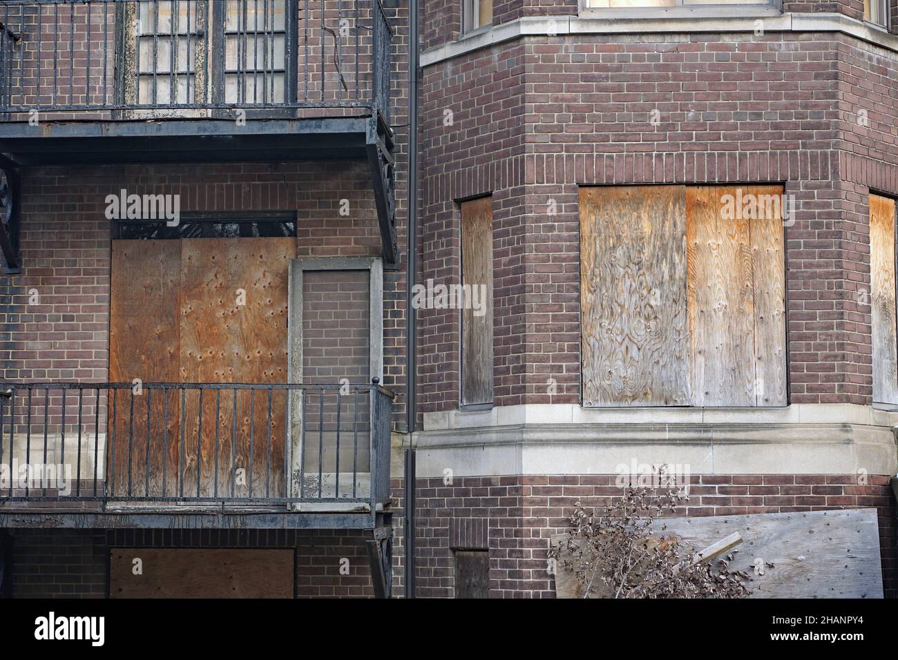 old abandoned apartment building with boarded up windows and rusty iron balconies Stock Photo