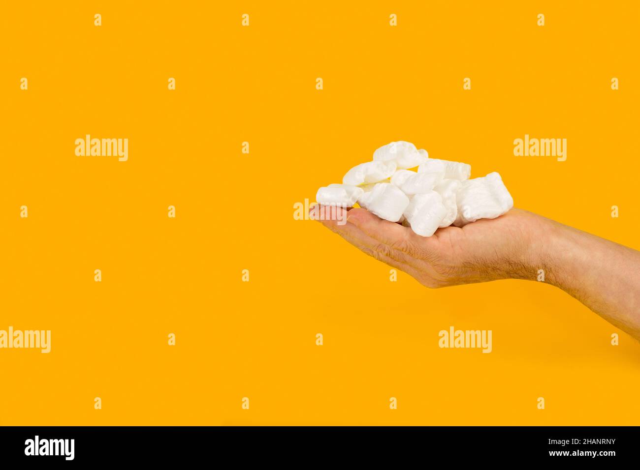 Packaging foam chips on a man hand on a yellow background Stock Photo