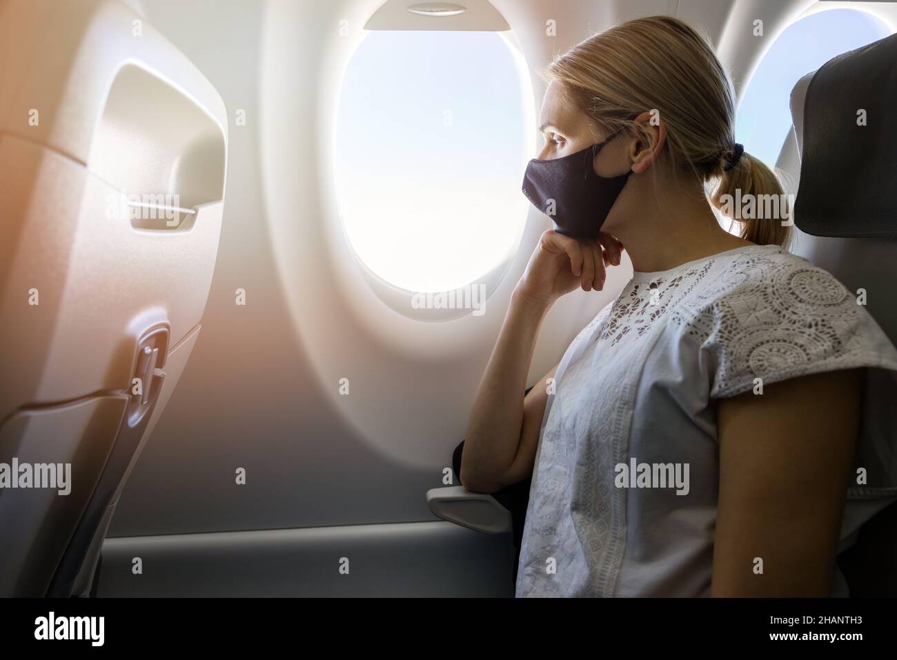 woman wearing face mask in airplane. new normal travel Stock Photo