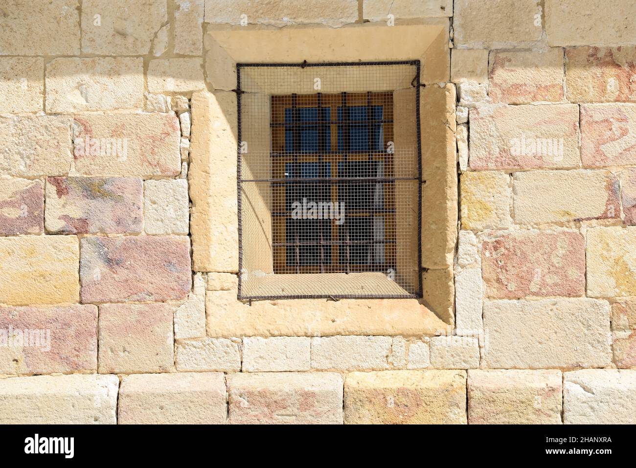 Old lattice window in the stone wall of a building in a town of Zamora, Spain, Europe illuminated by sunlight in summer. Stock Photo
