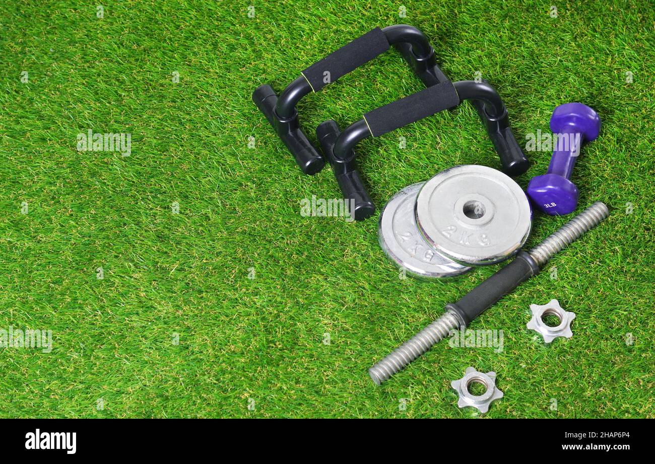 Fitness tools for physical training on the green artificial grass. Push up bars, dumbbells on the artificial turf. Copy space. Stock Photo