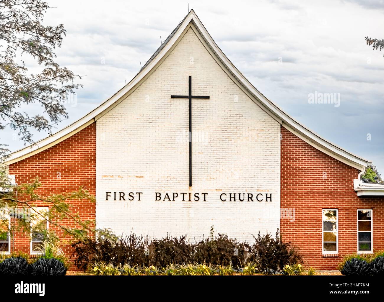 First Baptist church building with large cross, and colors of cream and red brick. Stock Photo