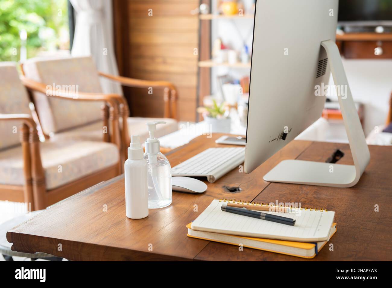 Work from home office gadget hygiene with computer and hand sanitizer protection from coronavirus outbreak or Covid-19  in living room Stock Photo