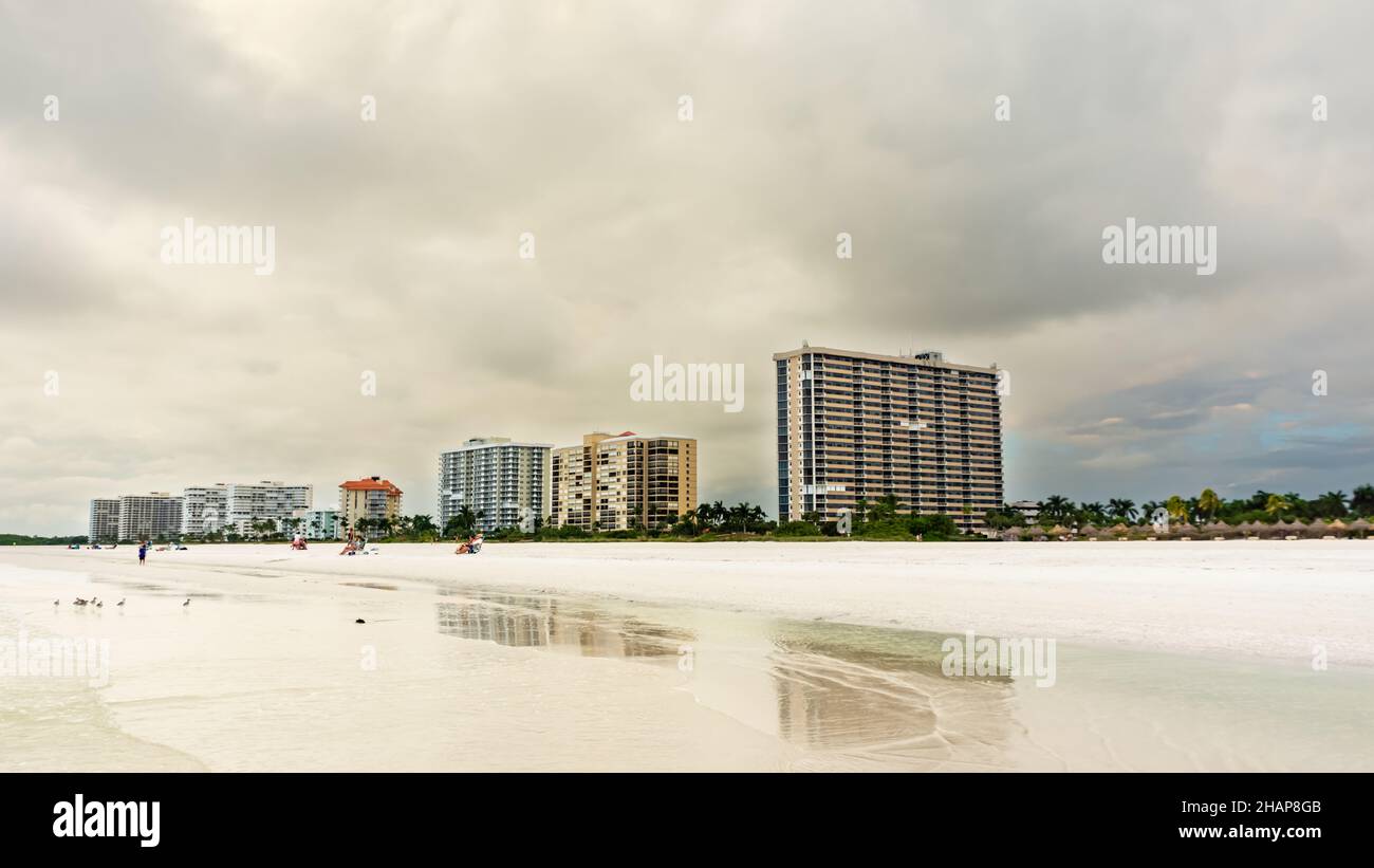 View on residence beach, showing water, pristine white sand and condominium buildings in Marco Island Florida on an overcast day. Stock Photo
