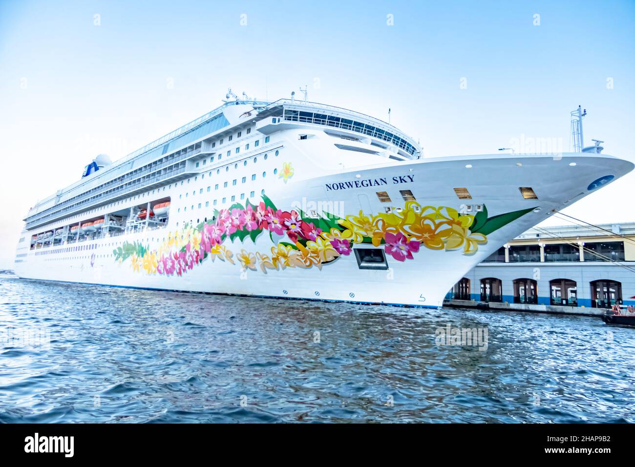 White Norwegian Sky cruise ship with yellow and pink flowers painted on the bow, docked at port in Cuba. Stock Photo