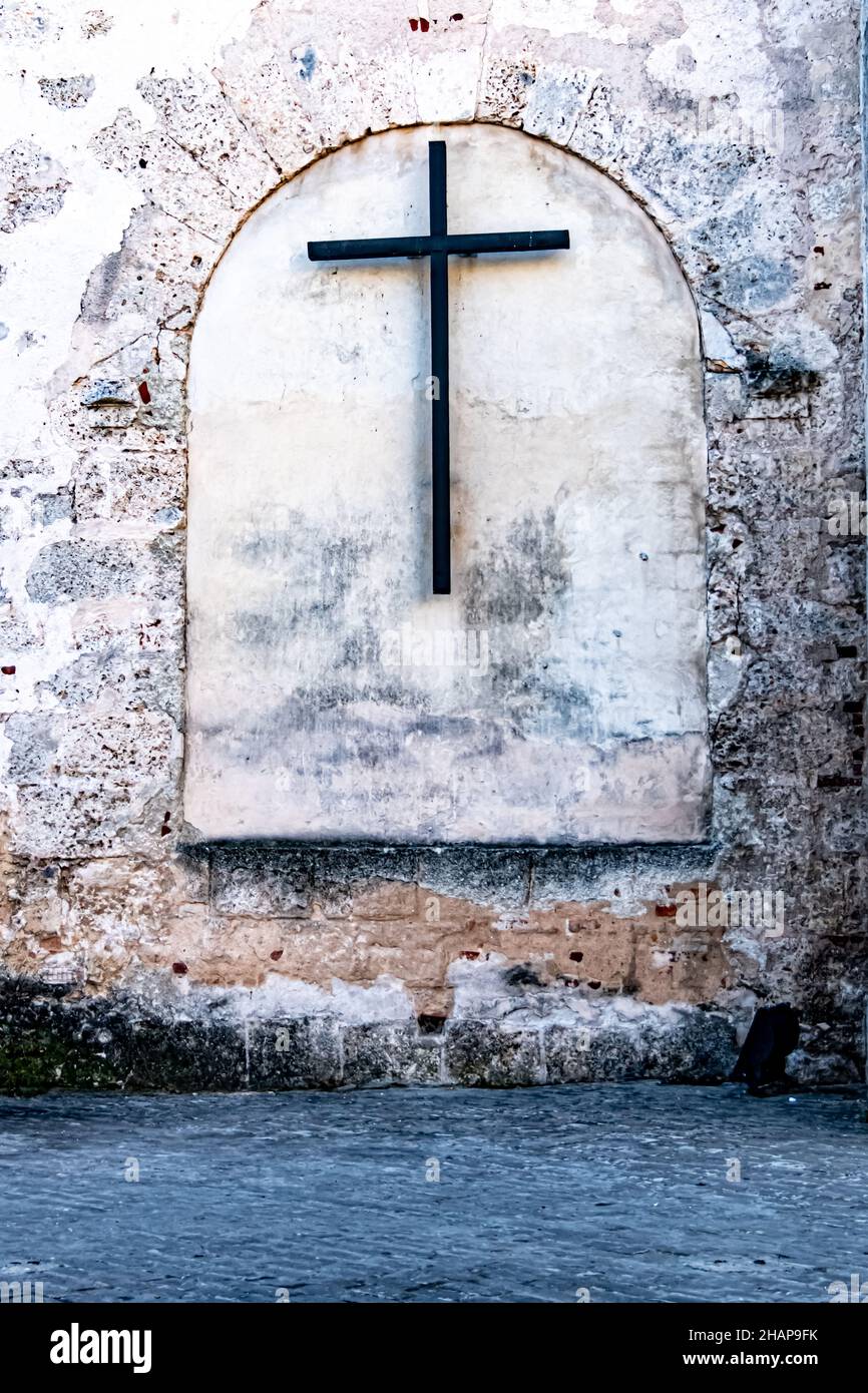 A black metal  cross on a grungy concrete wall in Havana Cuba Stock Photo