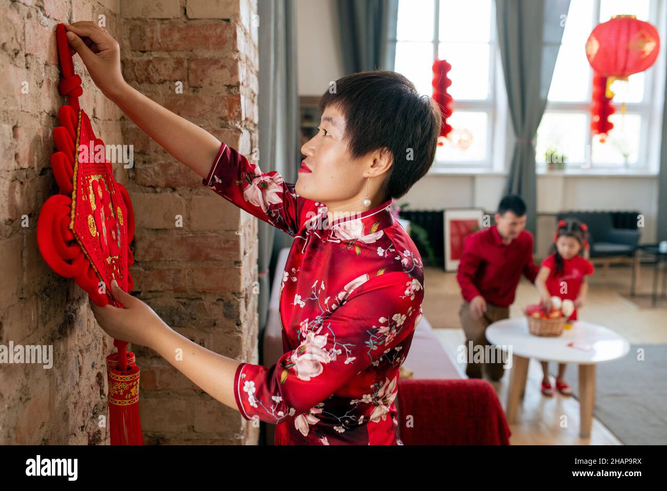 Pretty chinese woman in smart dress decoration walls of livingroom