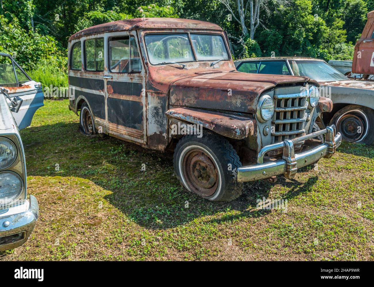 Vintage old rusty willys jeep station wagon parked outdoors fully intact with flat tires waiting for restoration all original with patina Stock Photo