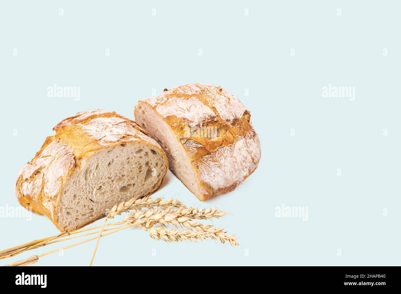 Beautiful view of cut loaf white bread and wheat ears isolated on blue ...