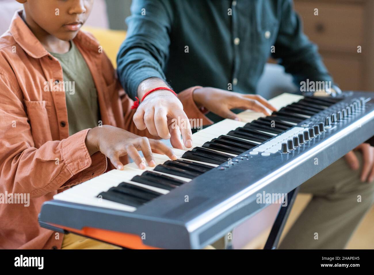 Hand of young teacher of music pointing at one of keys of piano keyboard during lesson in home environment Stock Photo