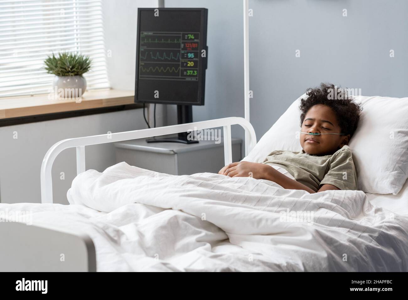 African little boy sleeping in bed after operation at hospital ward Stock Photo