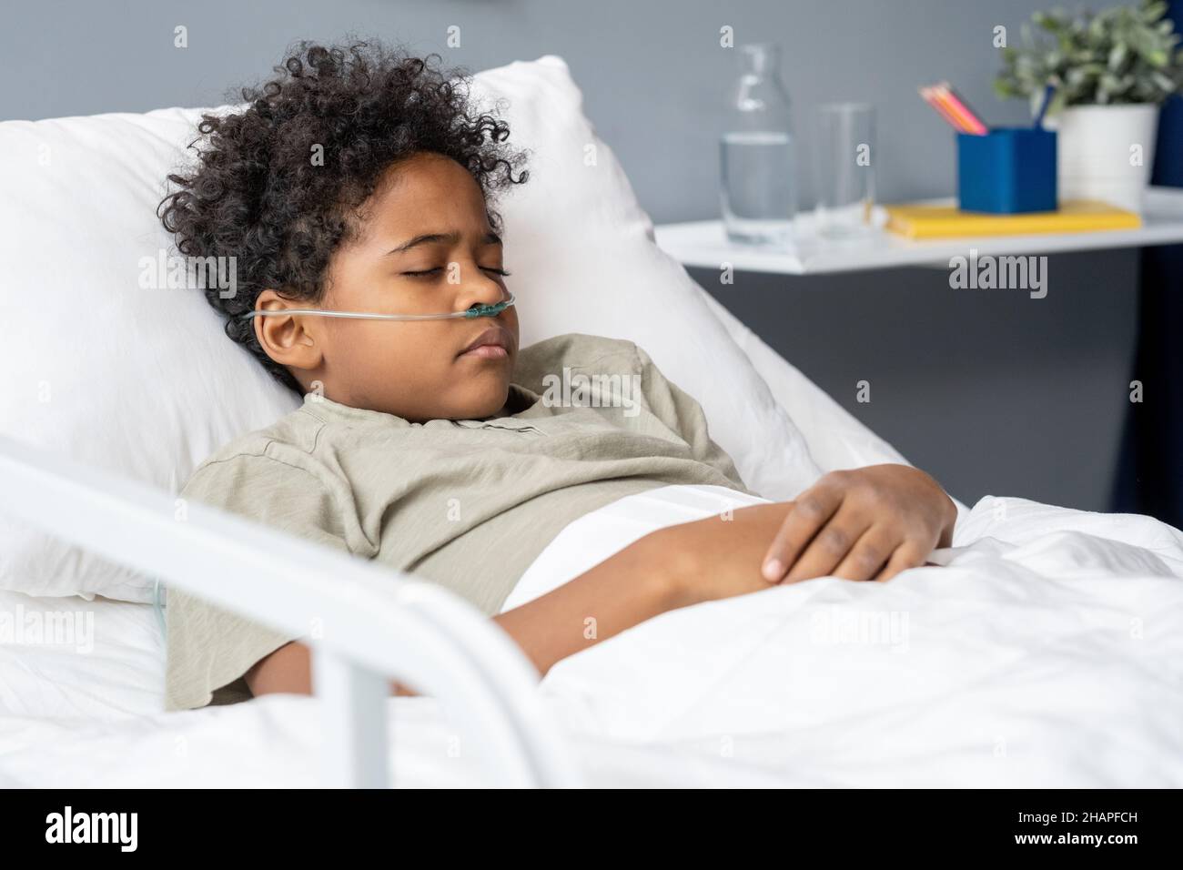 African little boy sleeping with oxygen tube in his nose in bed at hospital ward Stock Photo