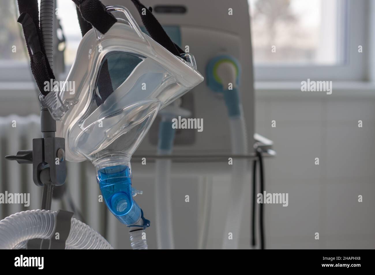 Noninvasive ventilation face mask, side view, on background medical ventilator in ICU in
