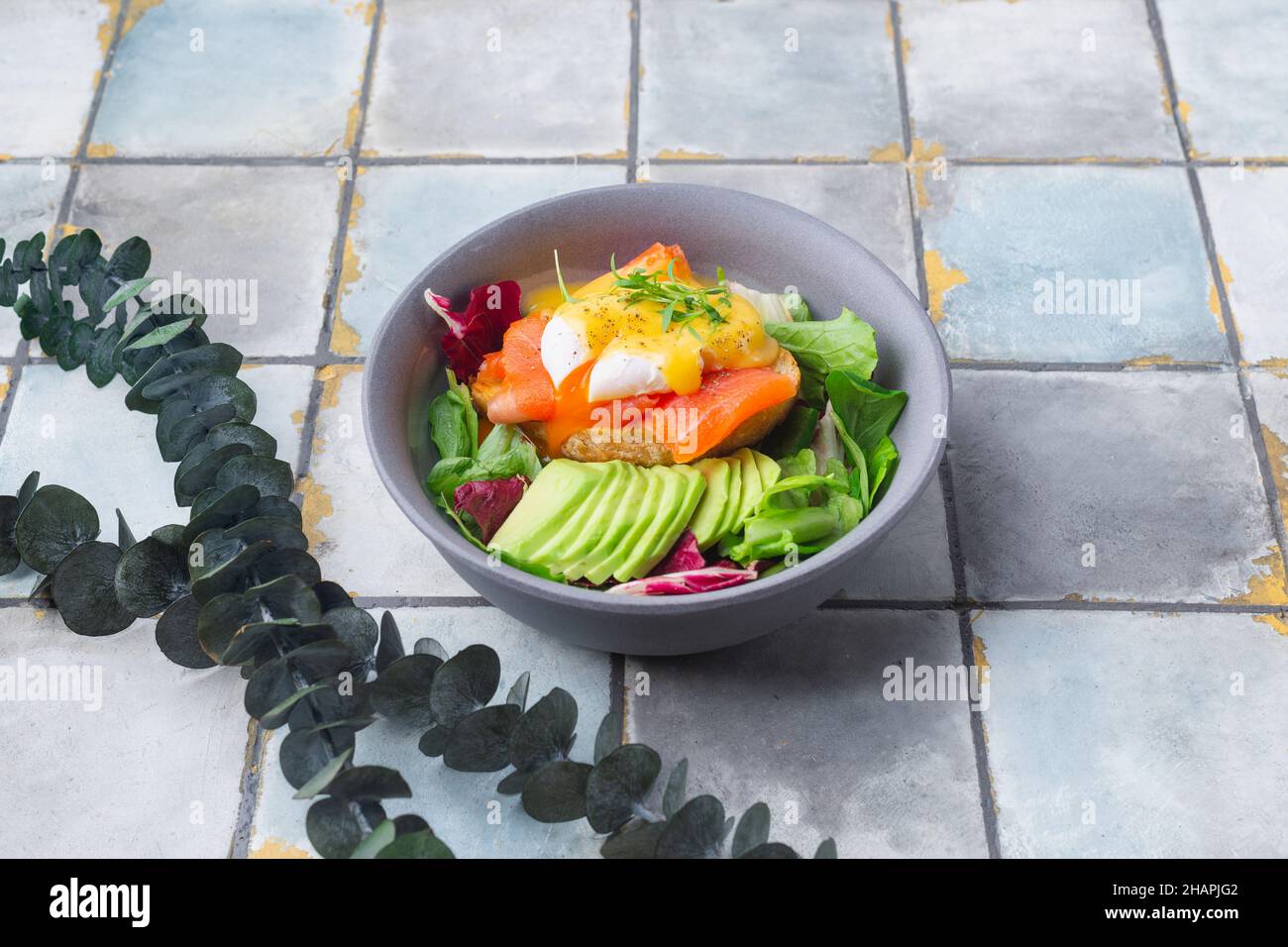 Delicious breakfast, brunch - poached egg, salmon, avocado, arugula salad on a tile background Stock Photo