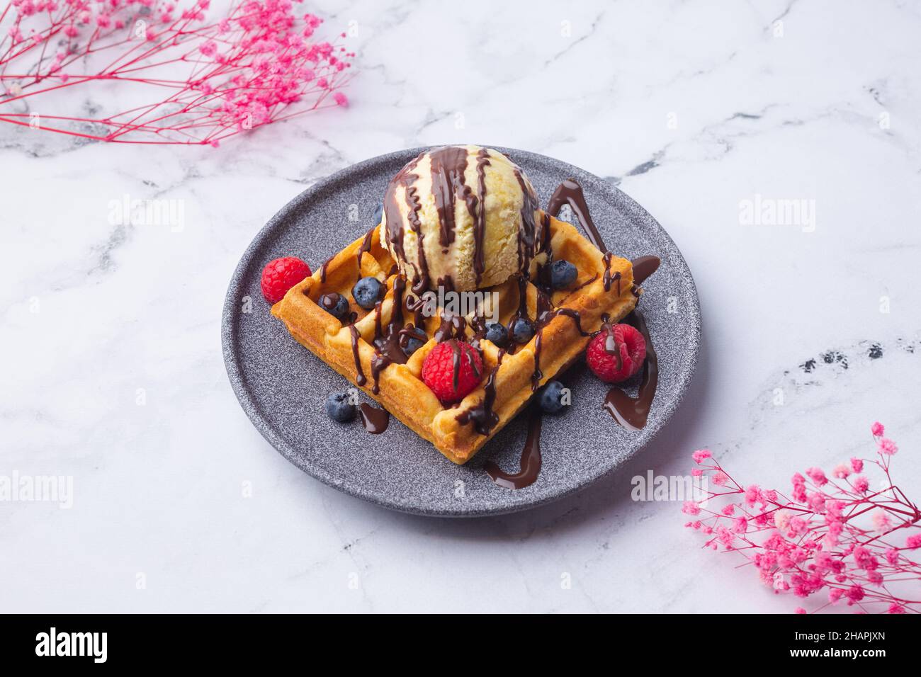 Belgian waffles with ice cream berries and flower on green Stock Photo